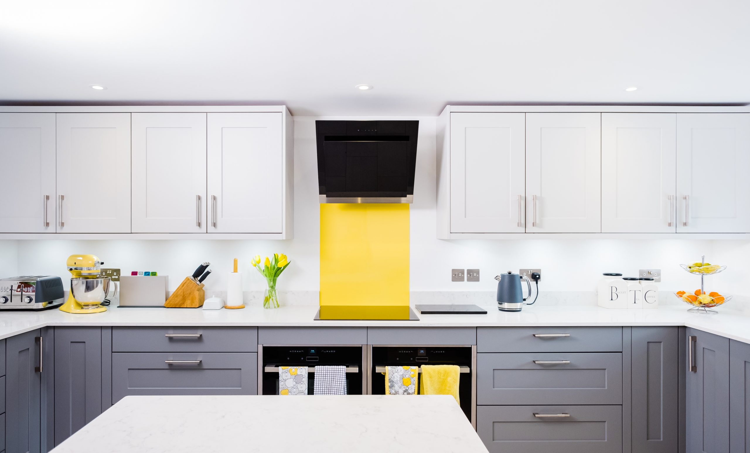 A grey kitchen with yellow splashback